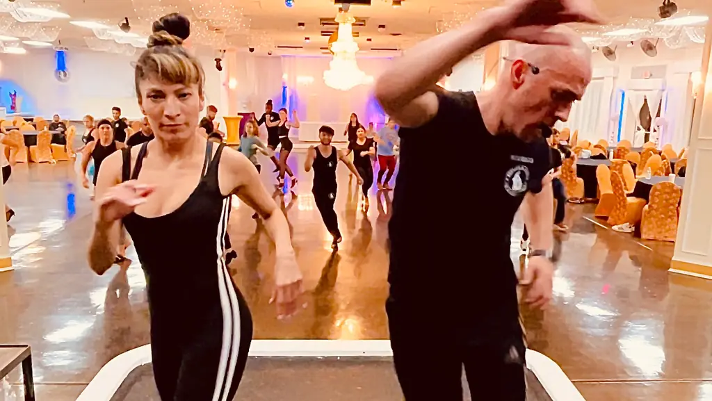 The instructors demonstrating a step in a ballroom with a chandelier