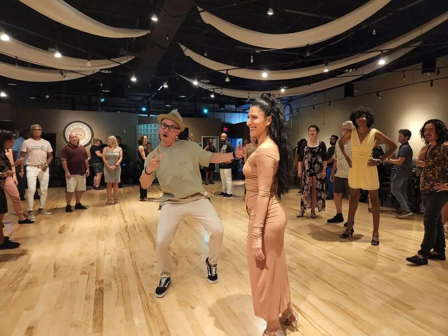 A Latin social on the wood floor, a couple dancing in the middle of the room